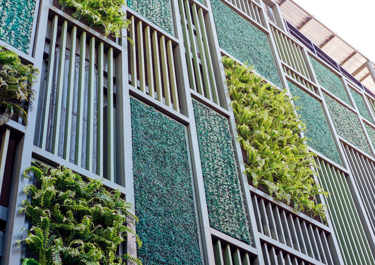 Die Fassade eines Gebäudes die mit diversen Pflanzen begrünt ist.