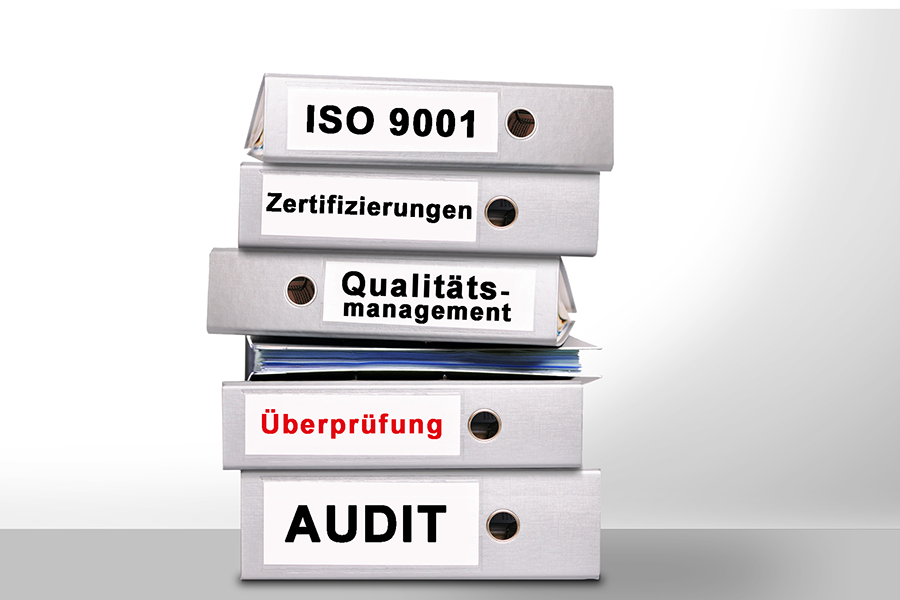 Ein Stapel zu bearbeitender Ordner zur neuen ISO 9001 Norm